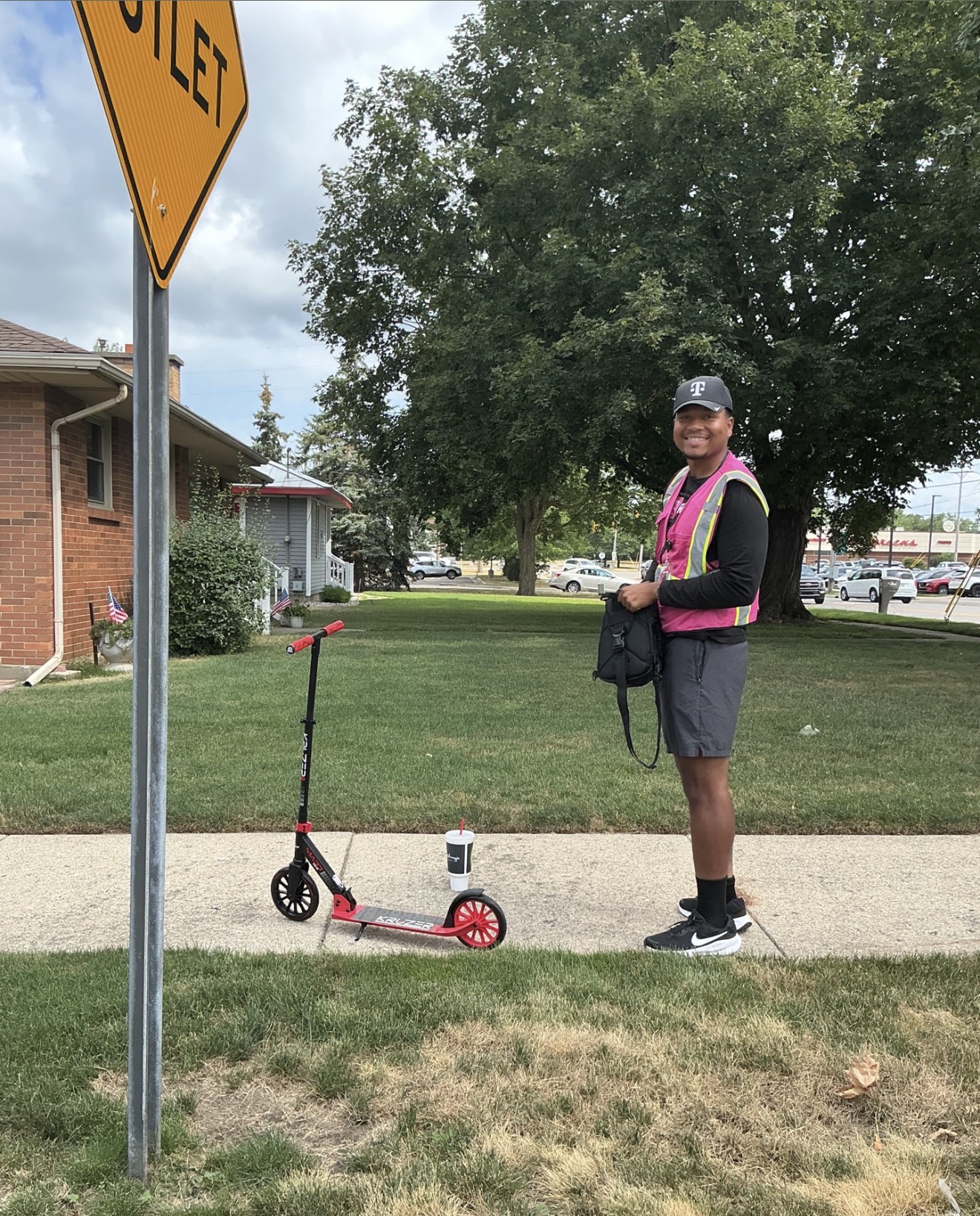 A field representative wearing a pink safety vest beside a scooter