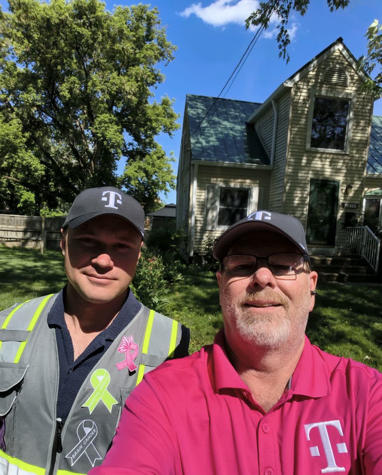 Two representatives wearing T-branded caps in a neighborhood